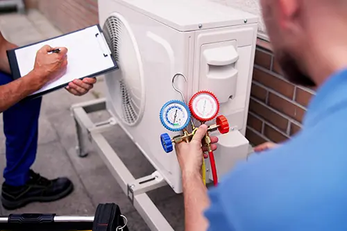 Design-Air Heating & Air Conditioning—Two AC technicians inspecting a unit outside a residence in Decatur, IL.
